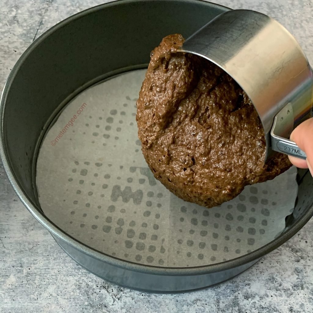 adding cake batter to a parchment lined baking pan