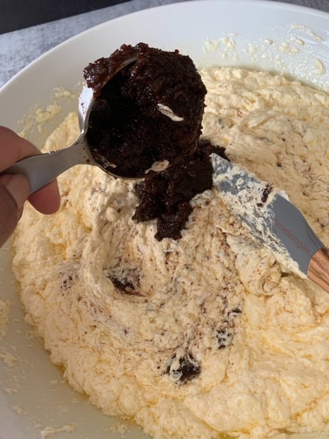 adding soaked fruit to black cake mixture