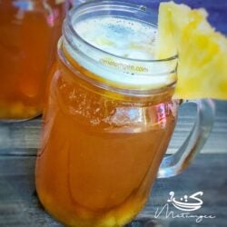 a glass of pine drink garnished with pineapple wedge