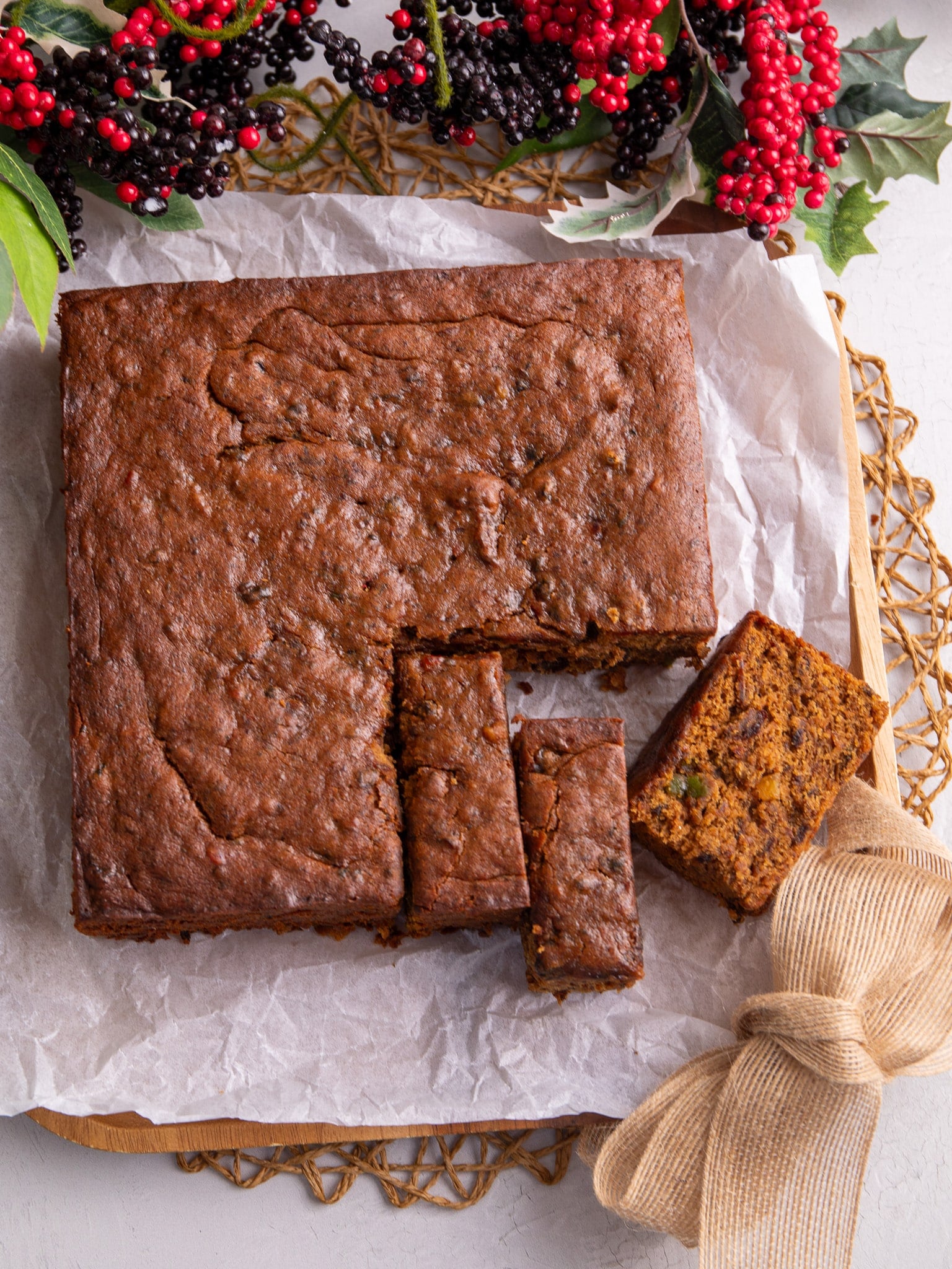 A square pan of Guyanese style fruit cake with three slices, one sitting side ways.