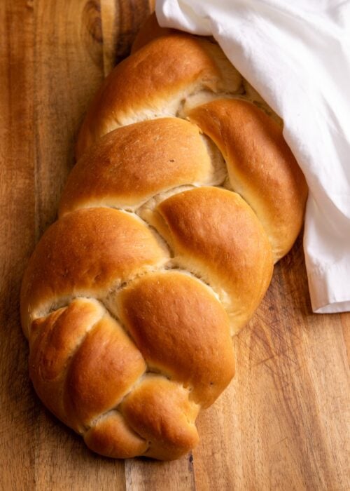 Guyanese plait bread on a wooden cutting board. The bread is wrapped in a white napkin.