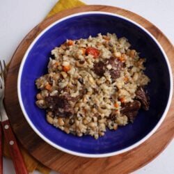 Instant pot cook up rice in a blue bowl resting on a wooden charger plate. The plate is on a white counter with a mustard napkin tucked under the left side