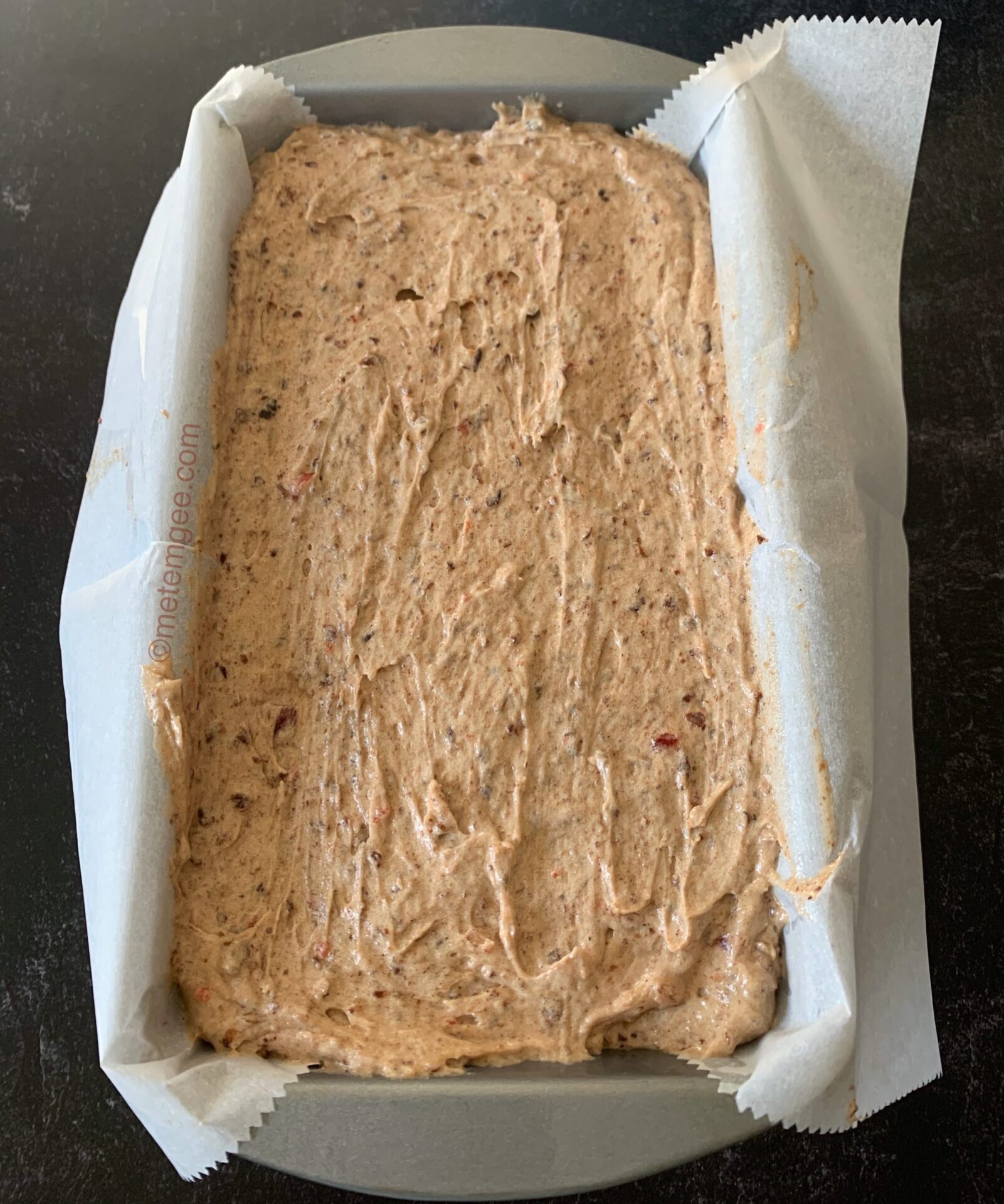 fruit cake batter added to parchment lined loaf pan