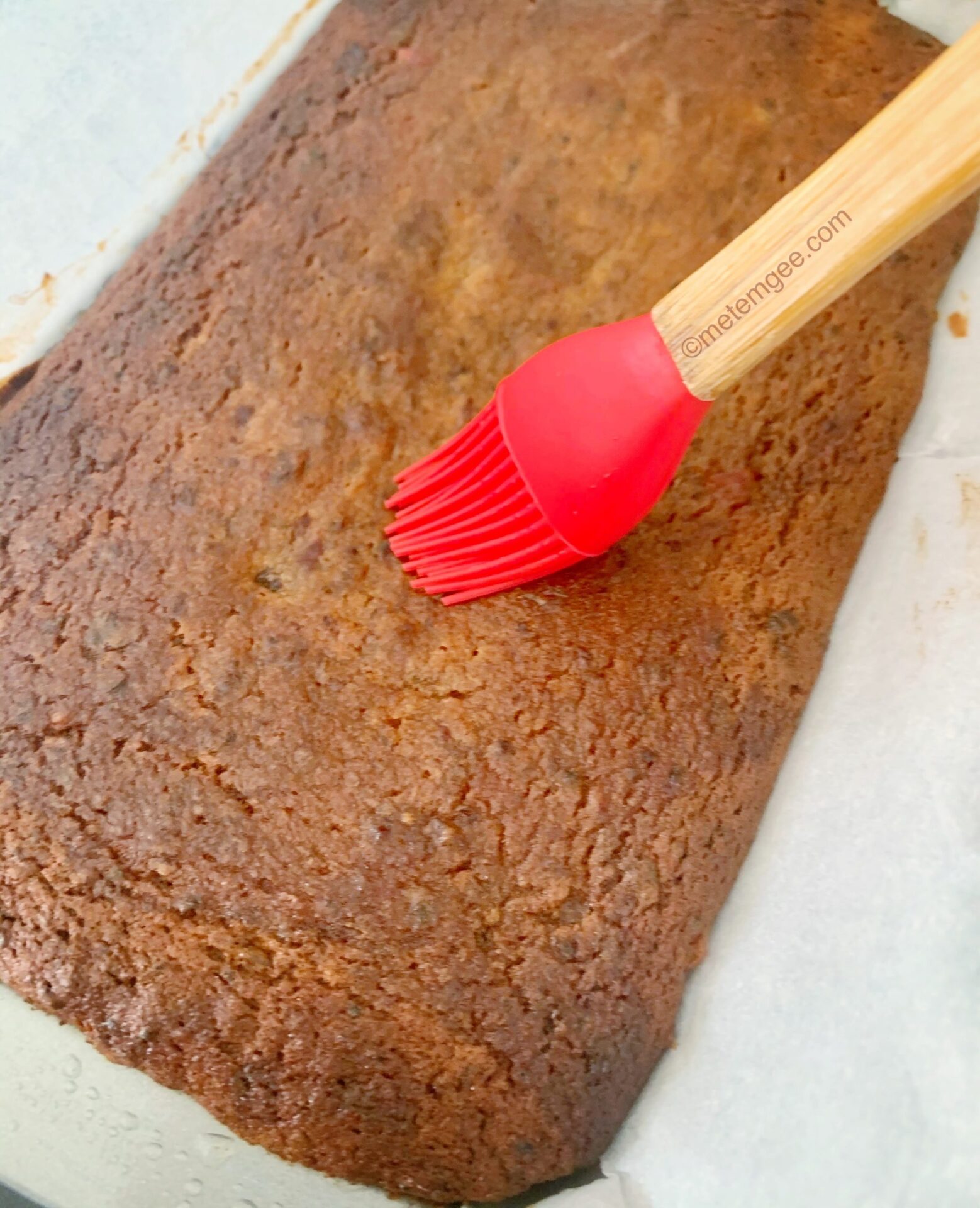 brushing orange liqueur into guyanese style fruit cake