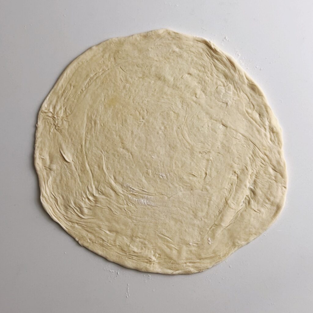 roti dough rollled into a flat disk on a white background