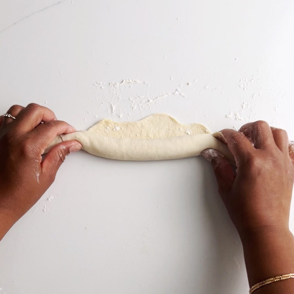 hands holding the dough on both ends and rolling into a log