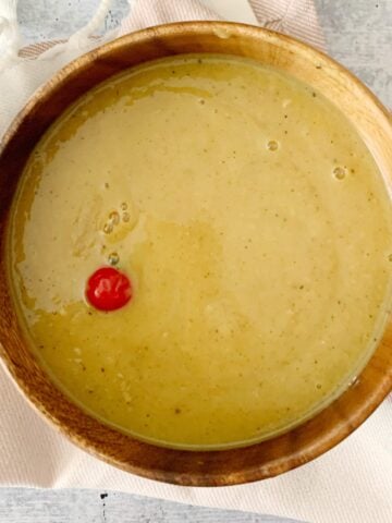 Dhal in a wooden bowl with a red wiri wiri pepper floating on top