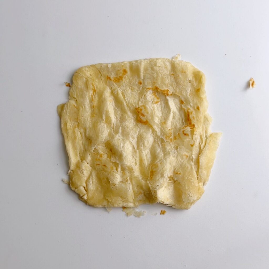 flaky square roti resting on a white back ground