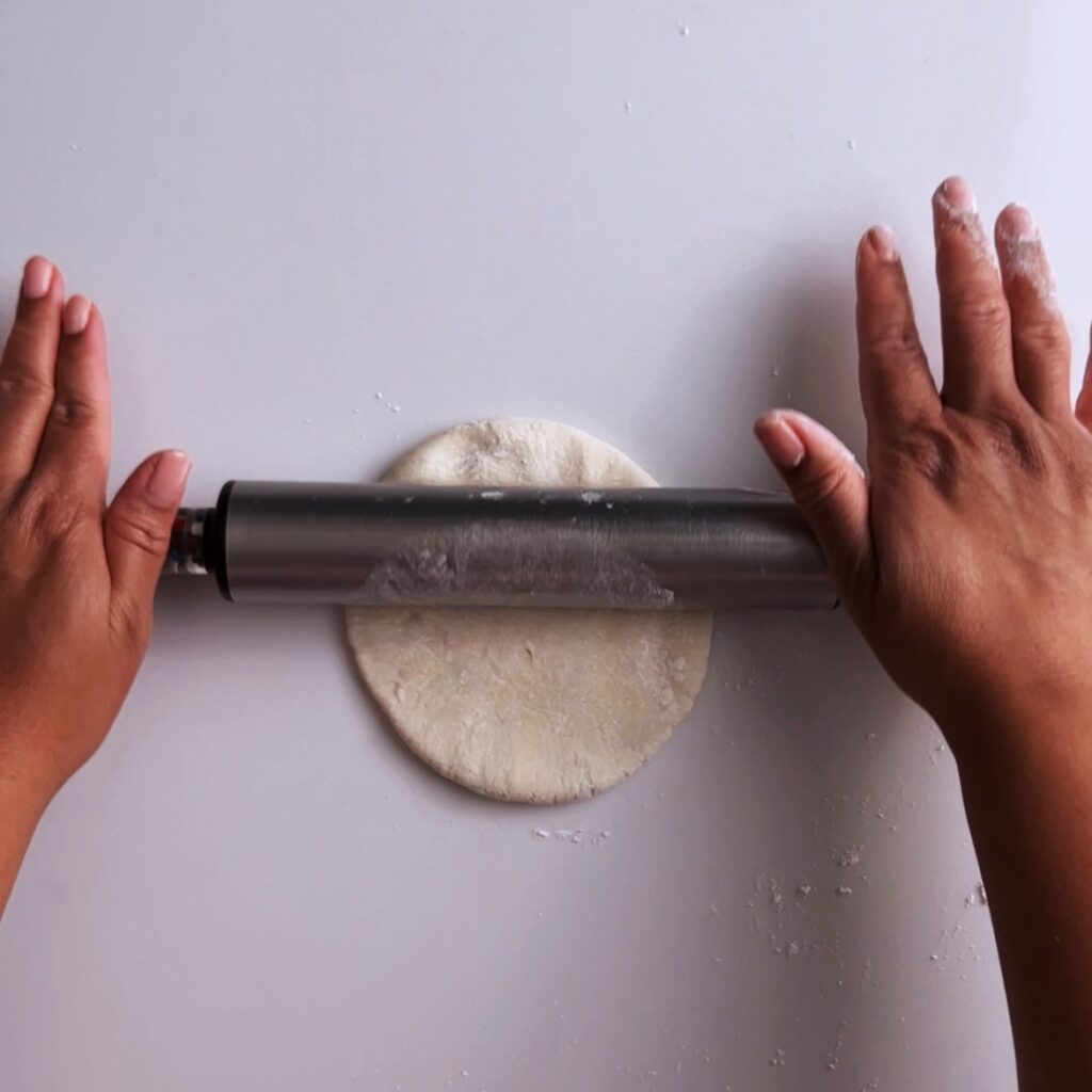 rolling out mashed potato roti with a rolling pin