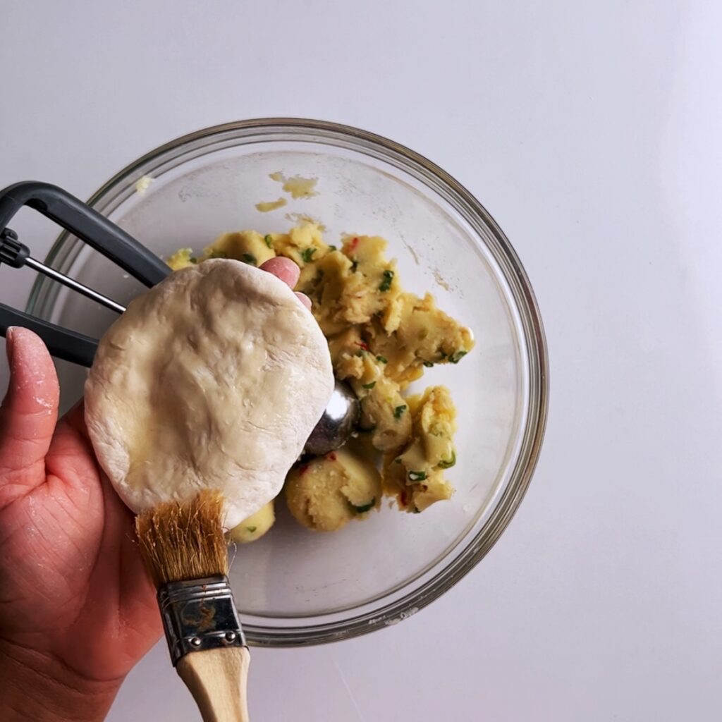 brushing potato roti dough with oil using a pastry brush