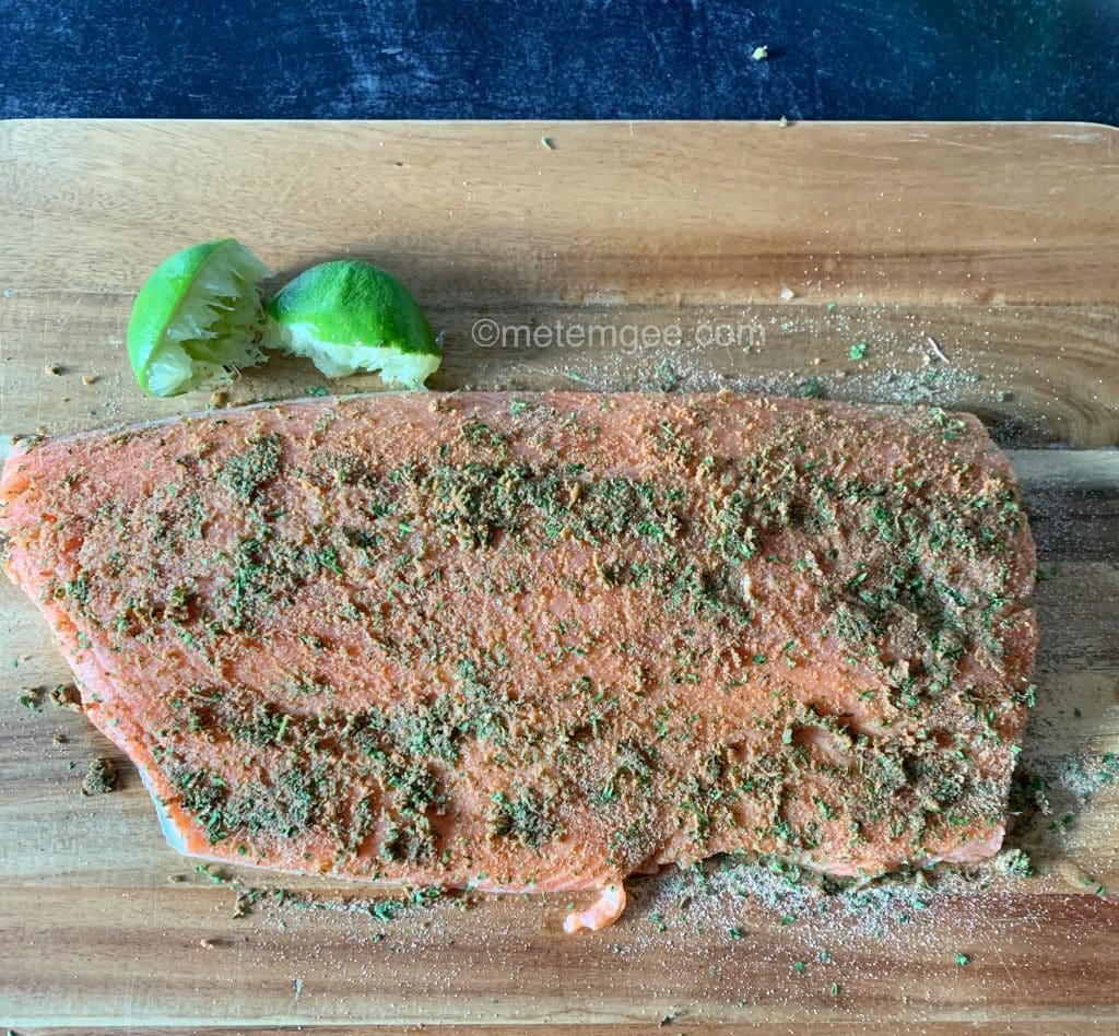 raw, seasoned salmon filet on a cutting board