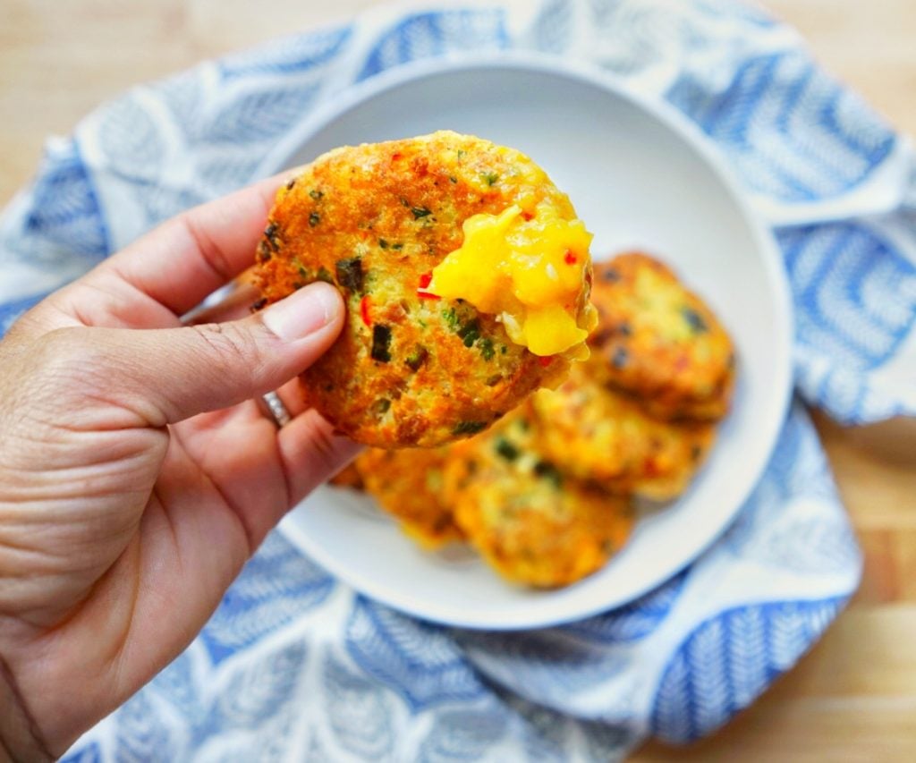 a hand holding a tuna patty with mango sour on it