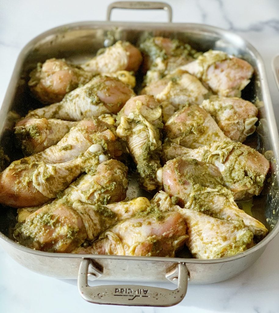 a baking tray of green seasoning marinated chicken legs