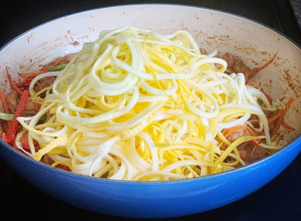 spiraled squash noodles added to pan