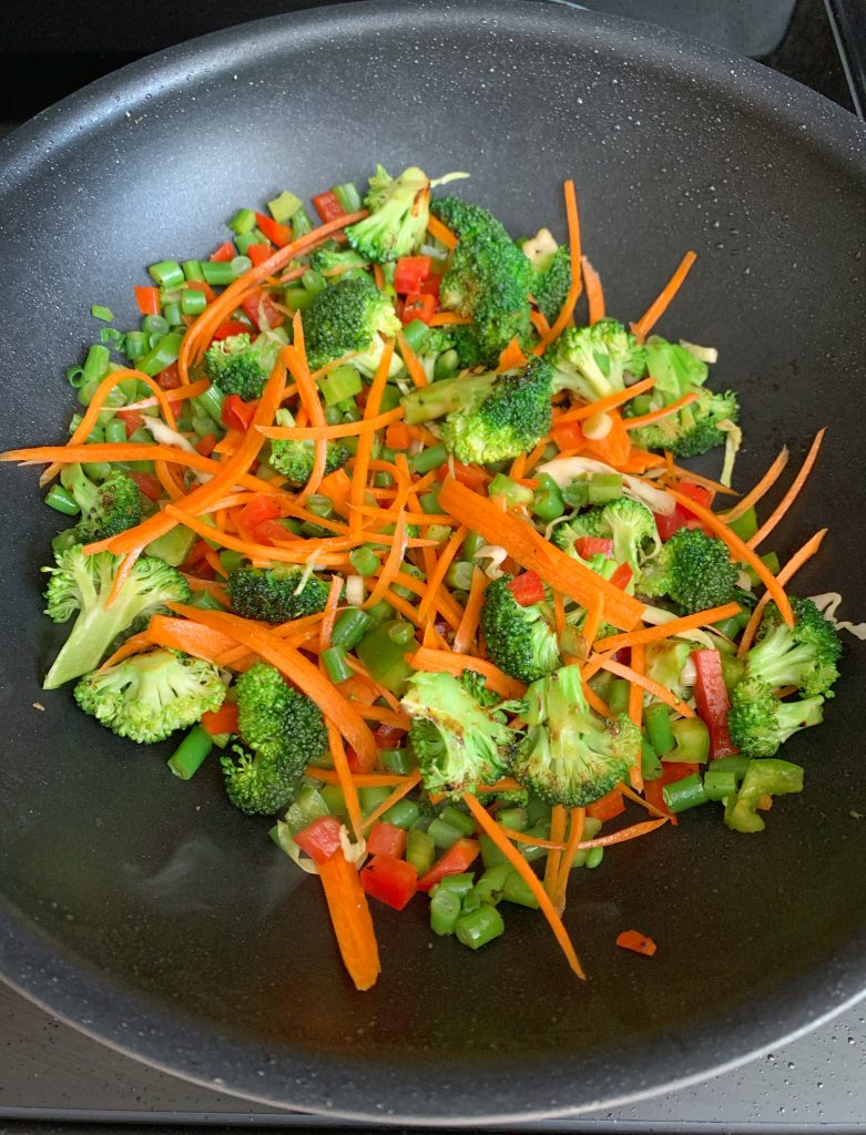 fresh vegetables added to a wok