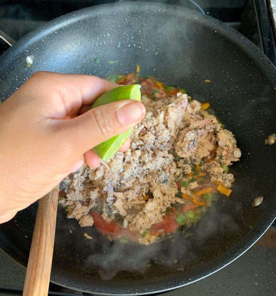 squeezing lime over sautéed canned salmon in a pan 