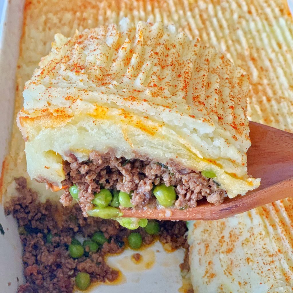 close up view of a slice of  shepherd's pie on a wooden spoon