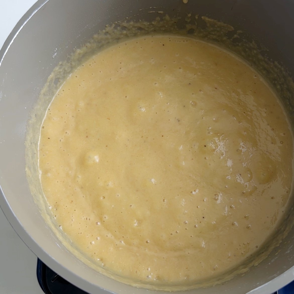 Plantain porridge in pot with visible bubbles from boiling