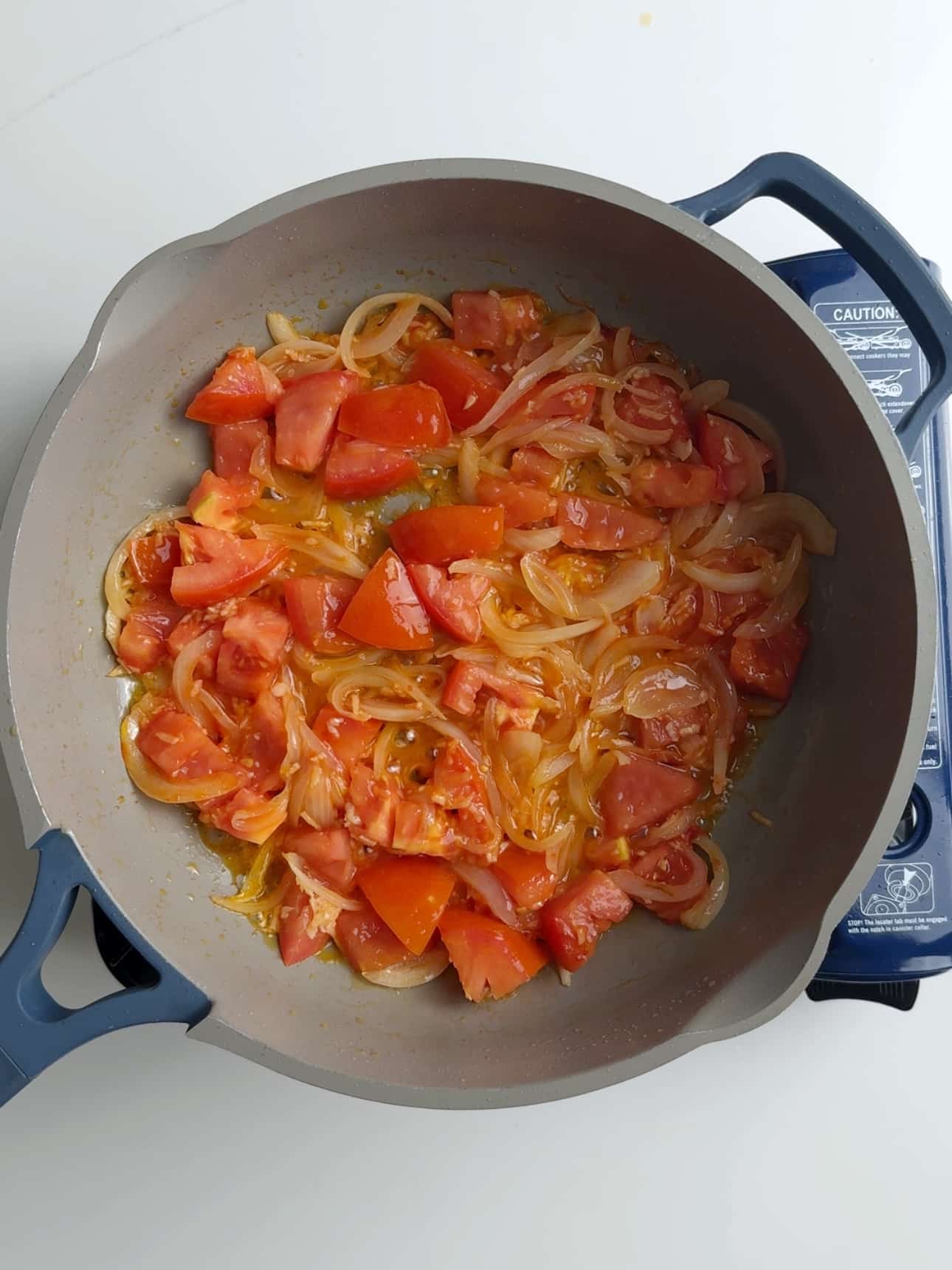 Cooked onions and tomatoes in a grey skillet