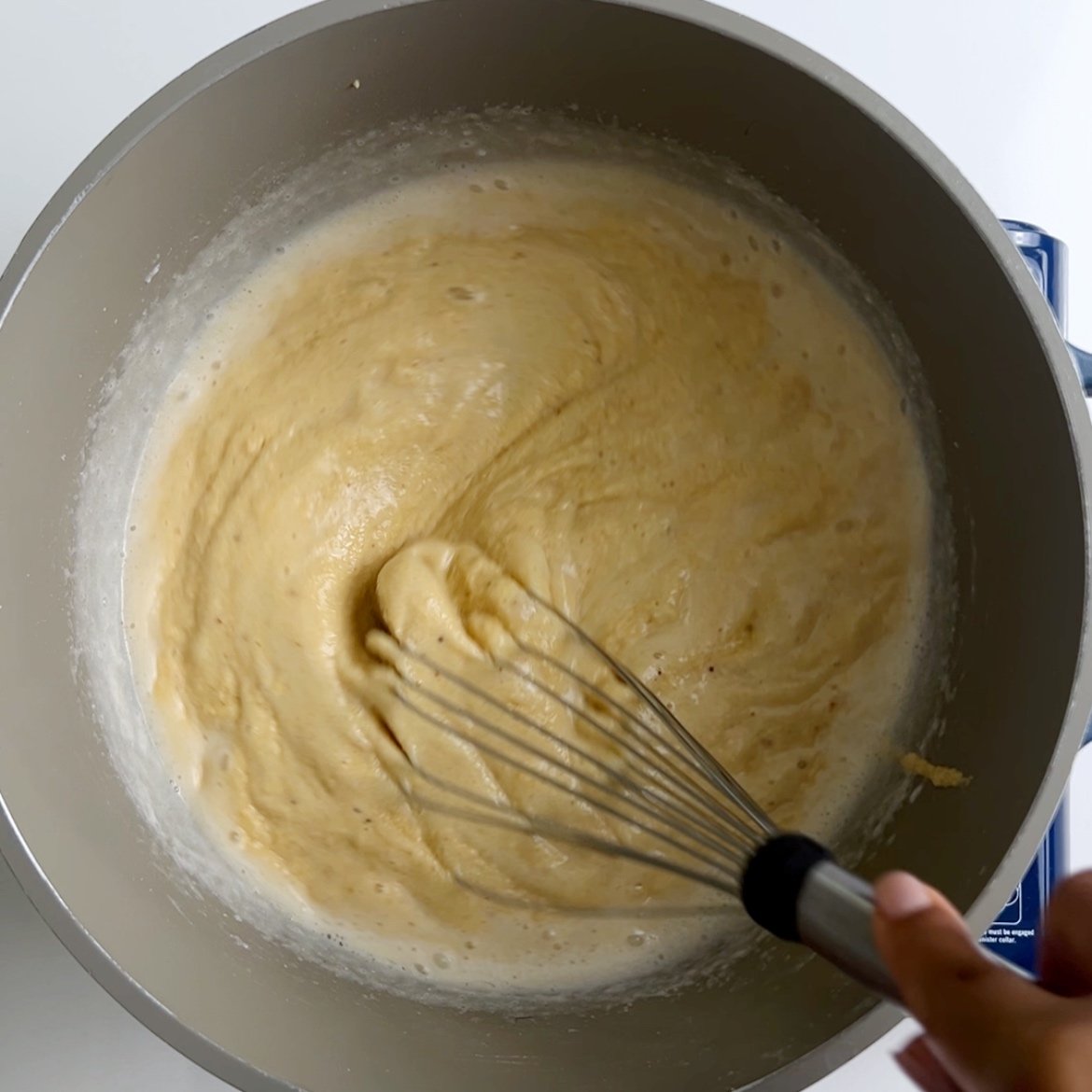 A whisk mixing together plantain porridge