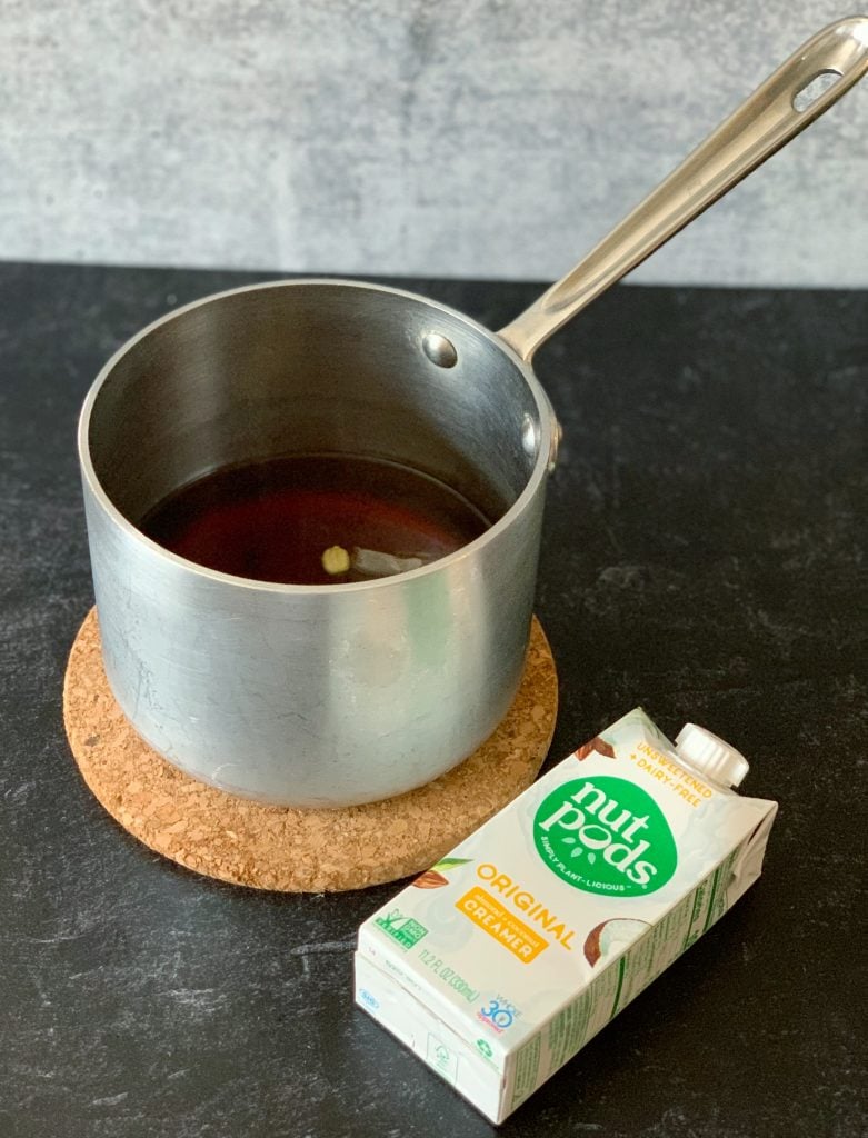 a small saucepan of spiced black tea beside a carton of Nut Pods creamer