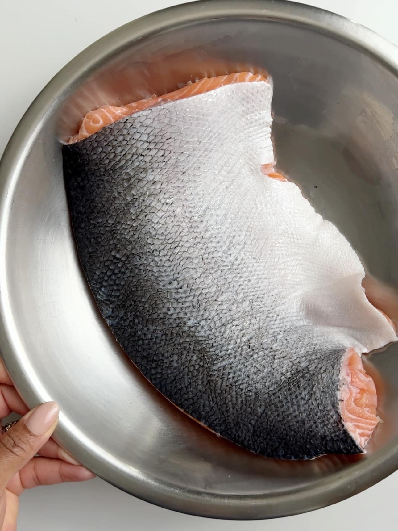 skin side up salmon in a stainless steel bowl, showing that all the scales have been removed.