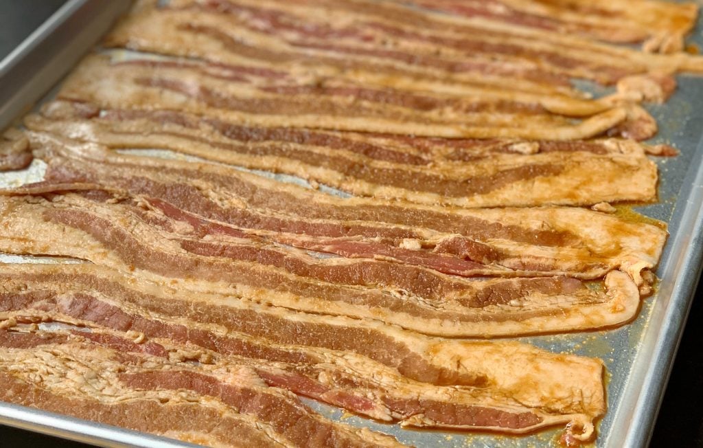 glazed bacon strips lined on a sheet pan