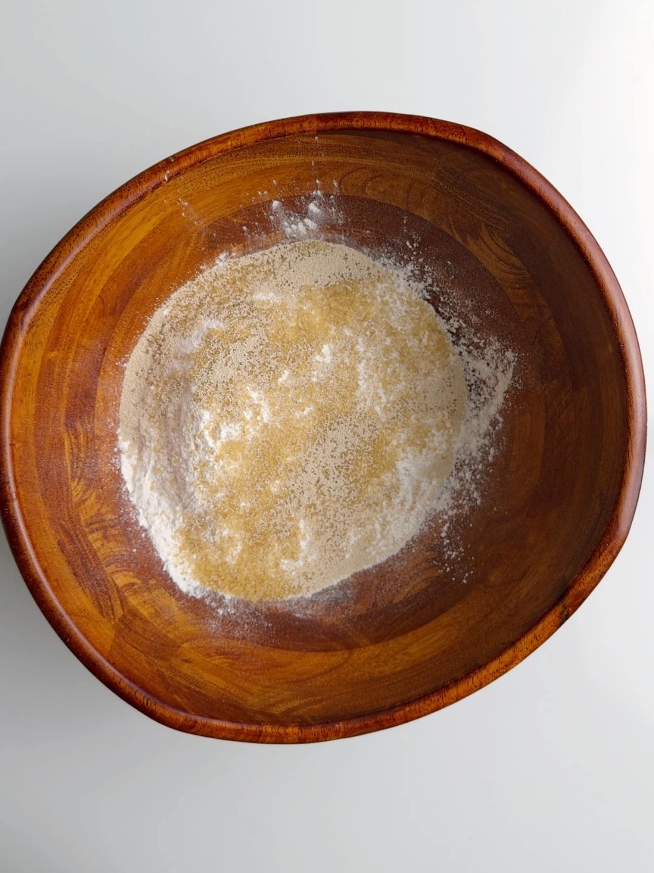 All of the dry ingredients for Pot Bake in a wooden bowl on a white surface.