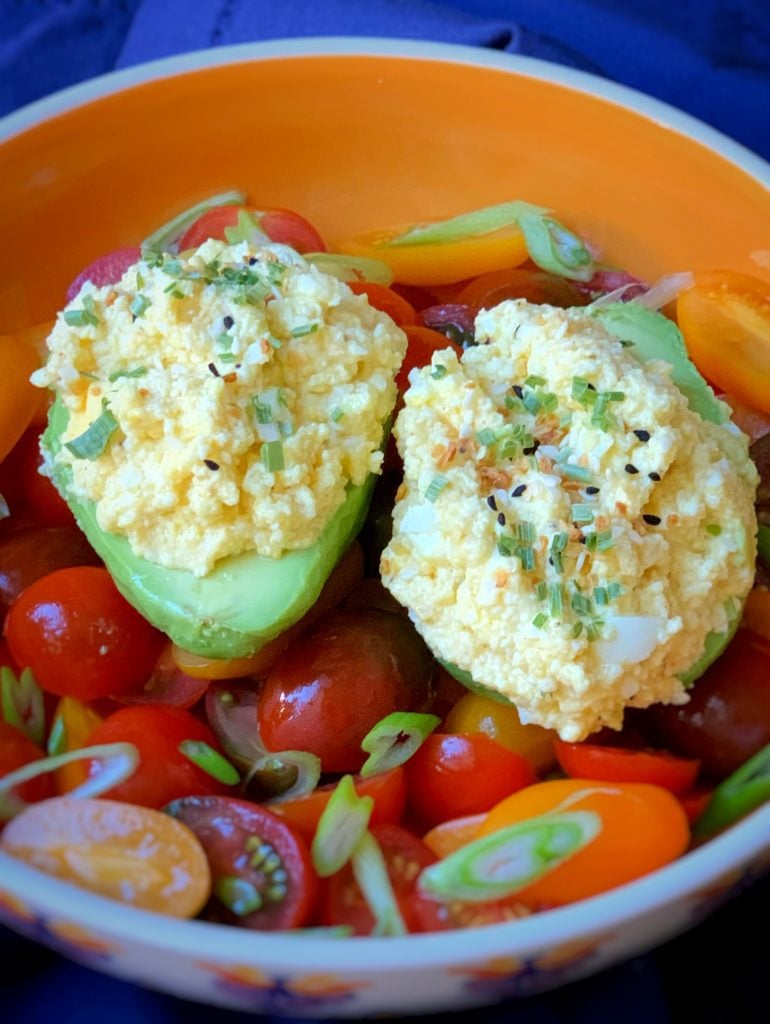 egg salad stuffed avocado over a bed of tomatoes