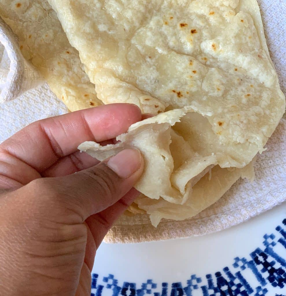 a hand holding cooked gluten free and grain free Guyanese roti to show the texture