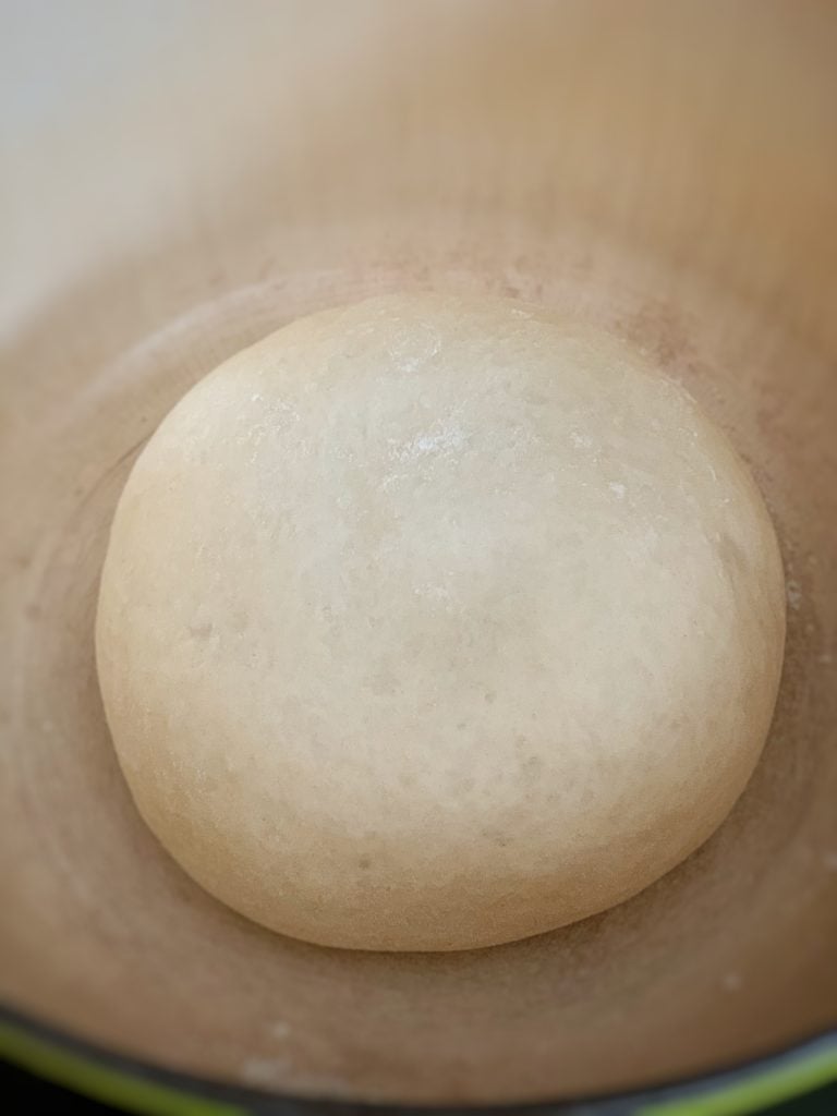 close up view of floured dough added to a dutch oven