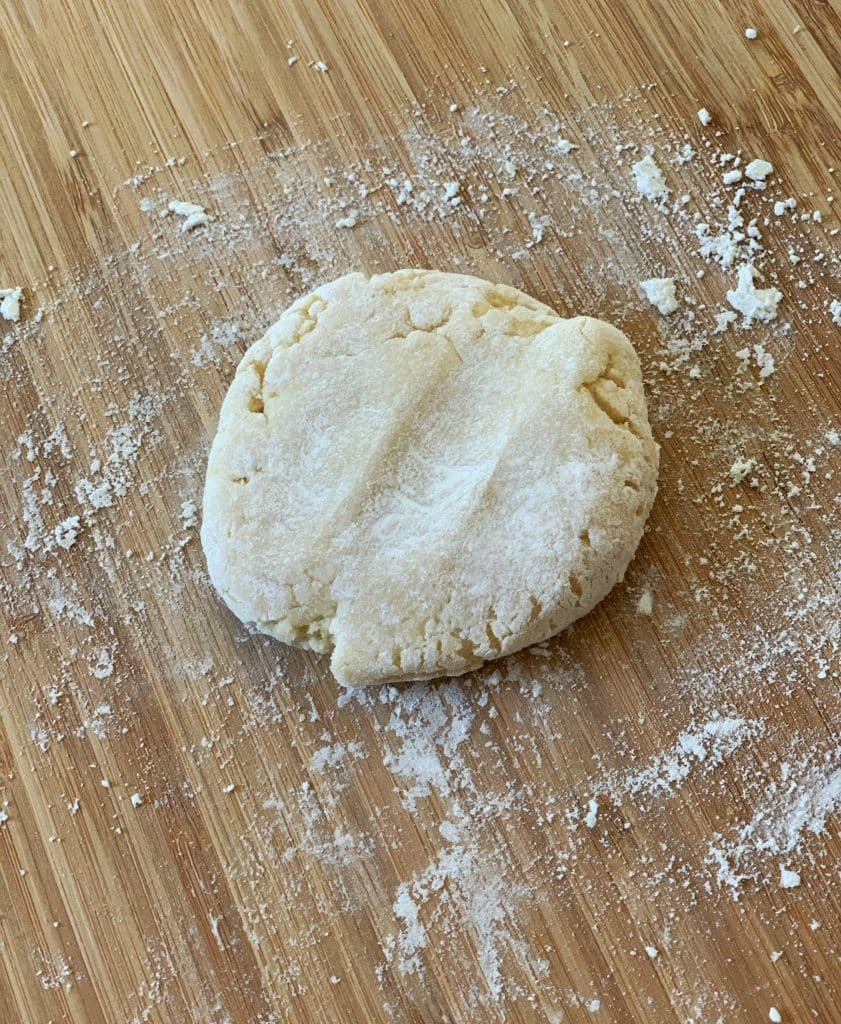 flattened dough ball on a floured surface
