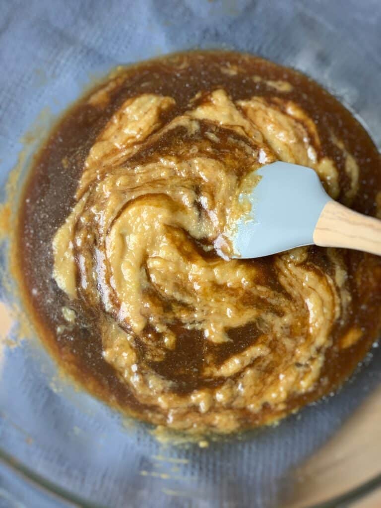 a spatula inserted into a bowl of wet and dry ingredients for carrot cake recipe