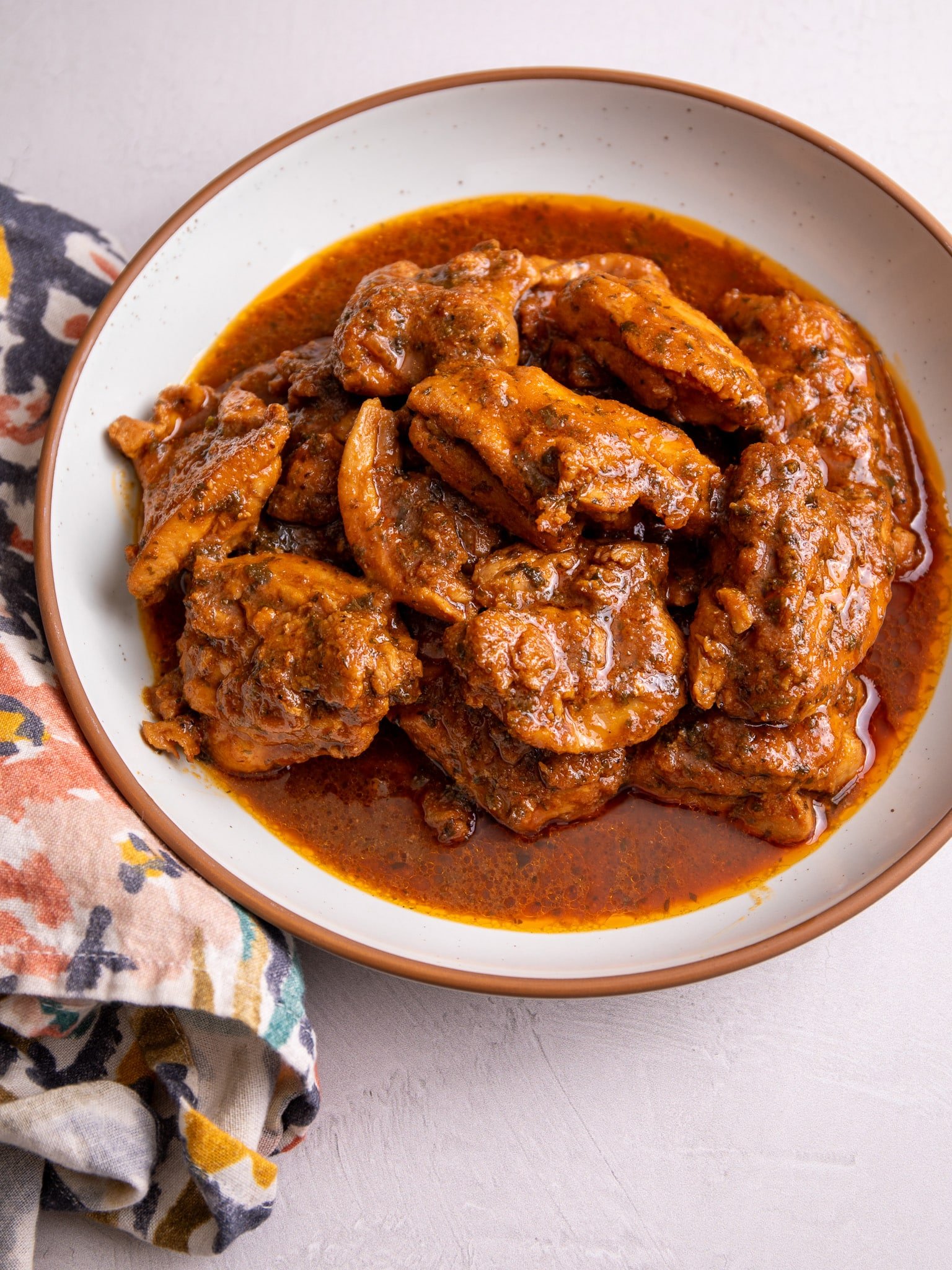 Caribbean Stew Chicken plated in a white bowl with a brown rim.