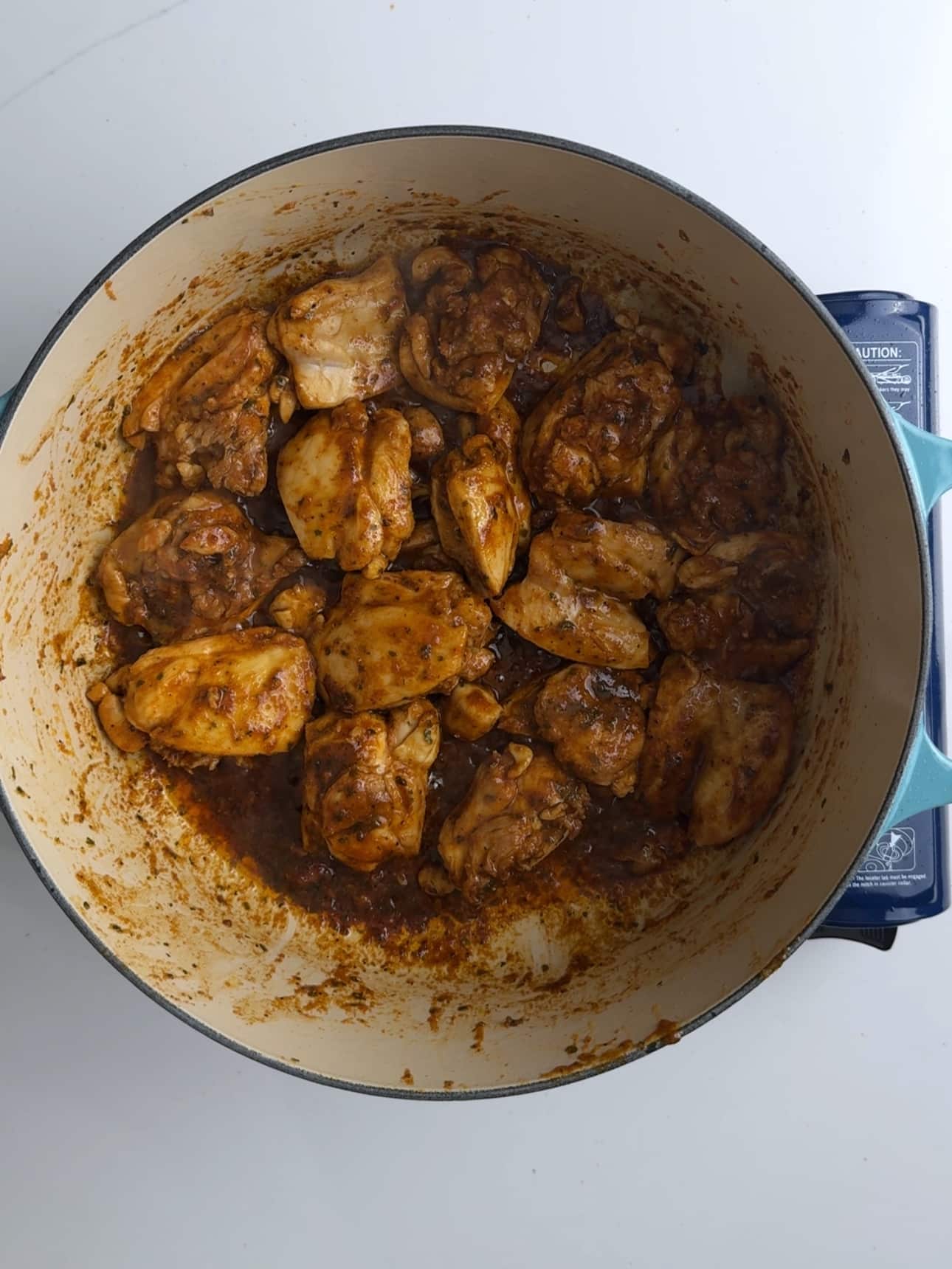 Chicken thighs seared with coconut aminos in a deep cast iron pot