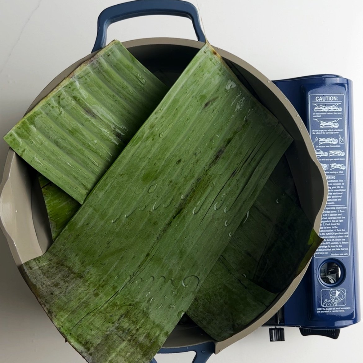 layering extra banana leaves into a pot to steam conkie
