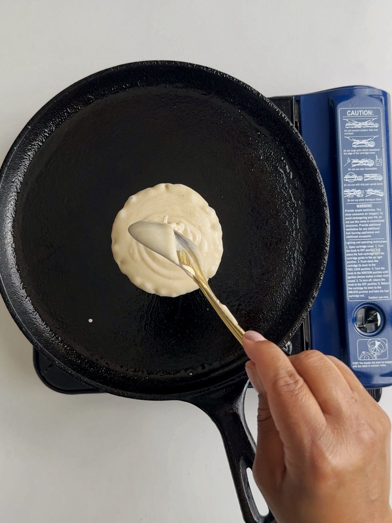 Adding batter to a Tawa with a spoon.