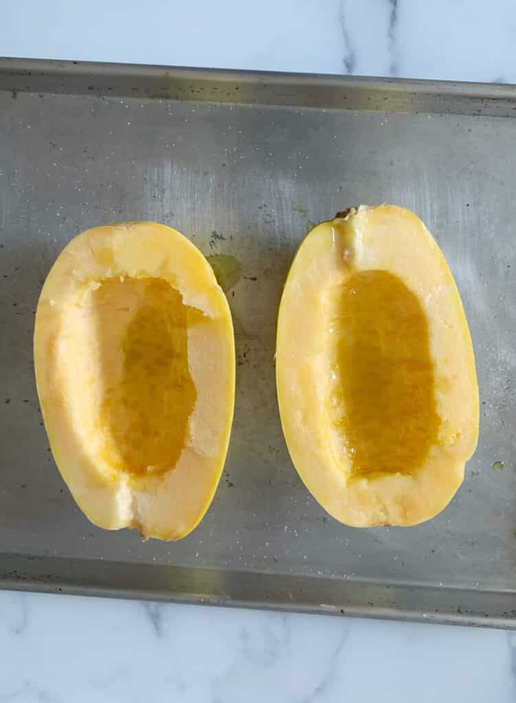spliced spaghetti squash drizzled with olive oil on a baking sheet