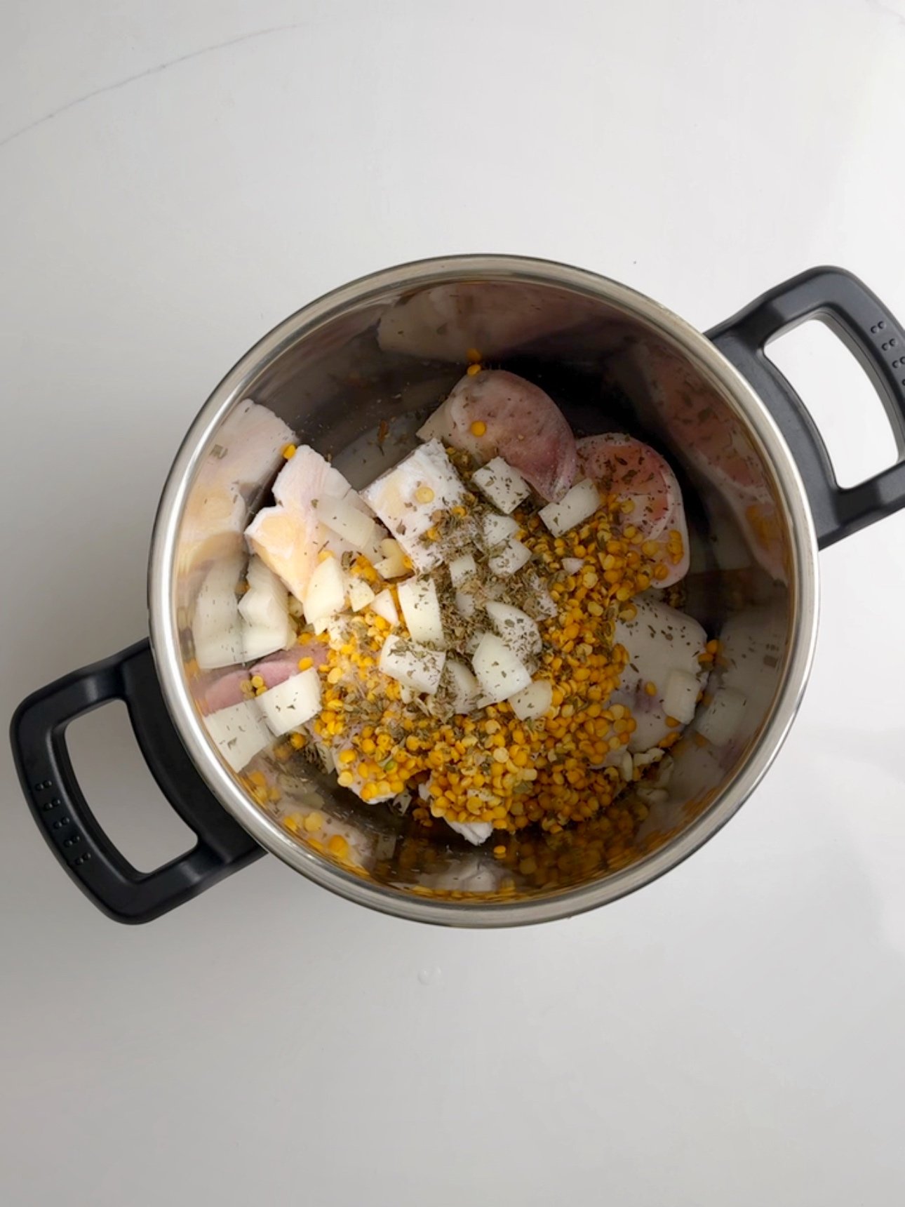 Cow heel, split peas, onion and garlic with dried herbs in a pressure pot.