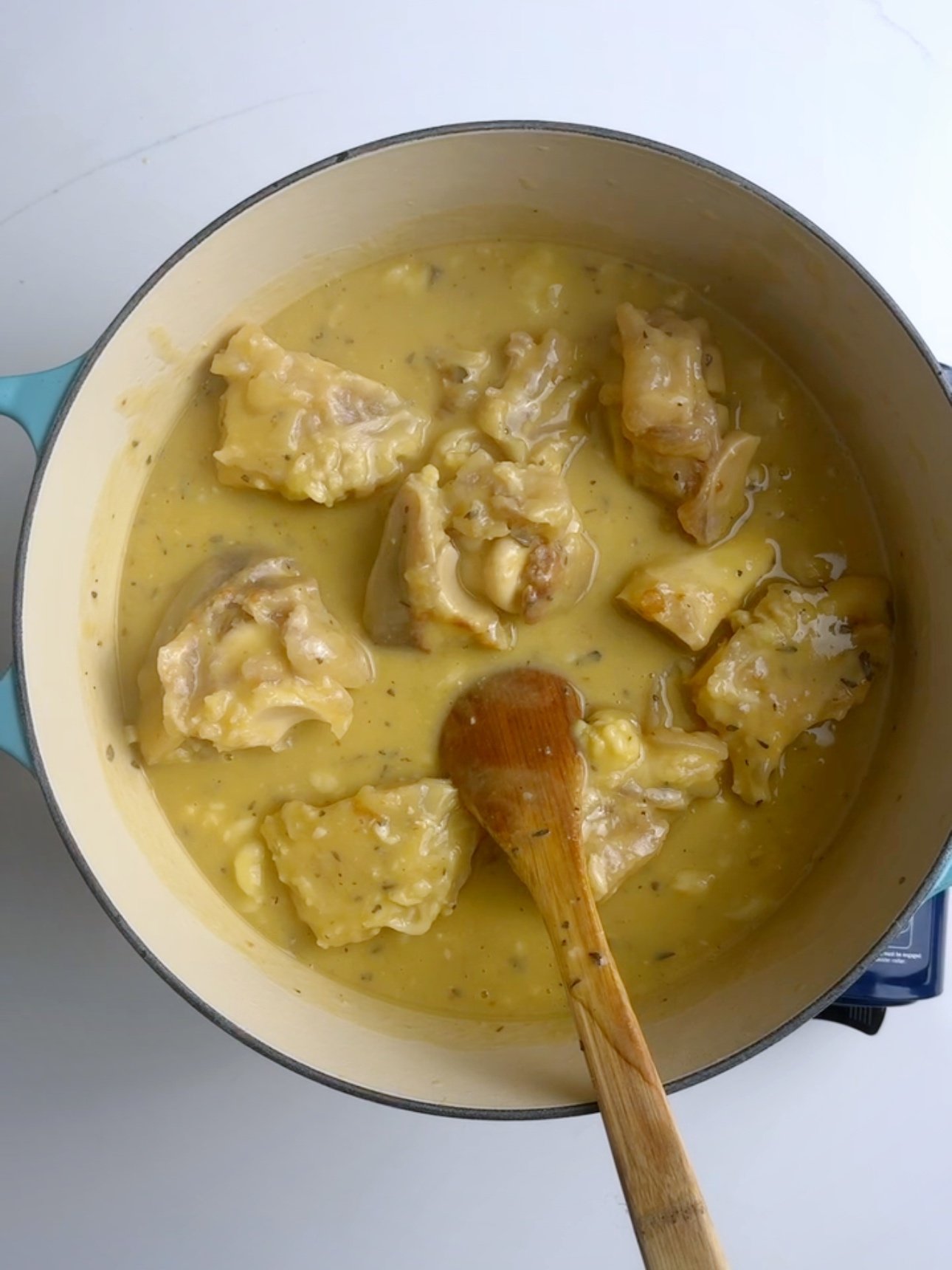 Adding the cooked cow heel to a large pot.