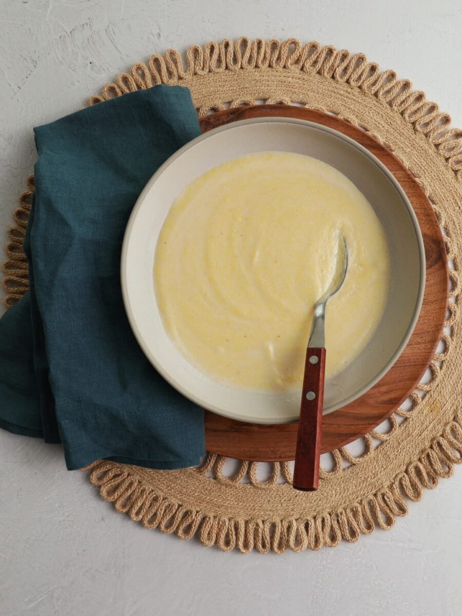 A bowl filled with cornmeal porridge with a spoon sitting in it.
