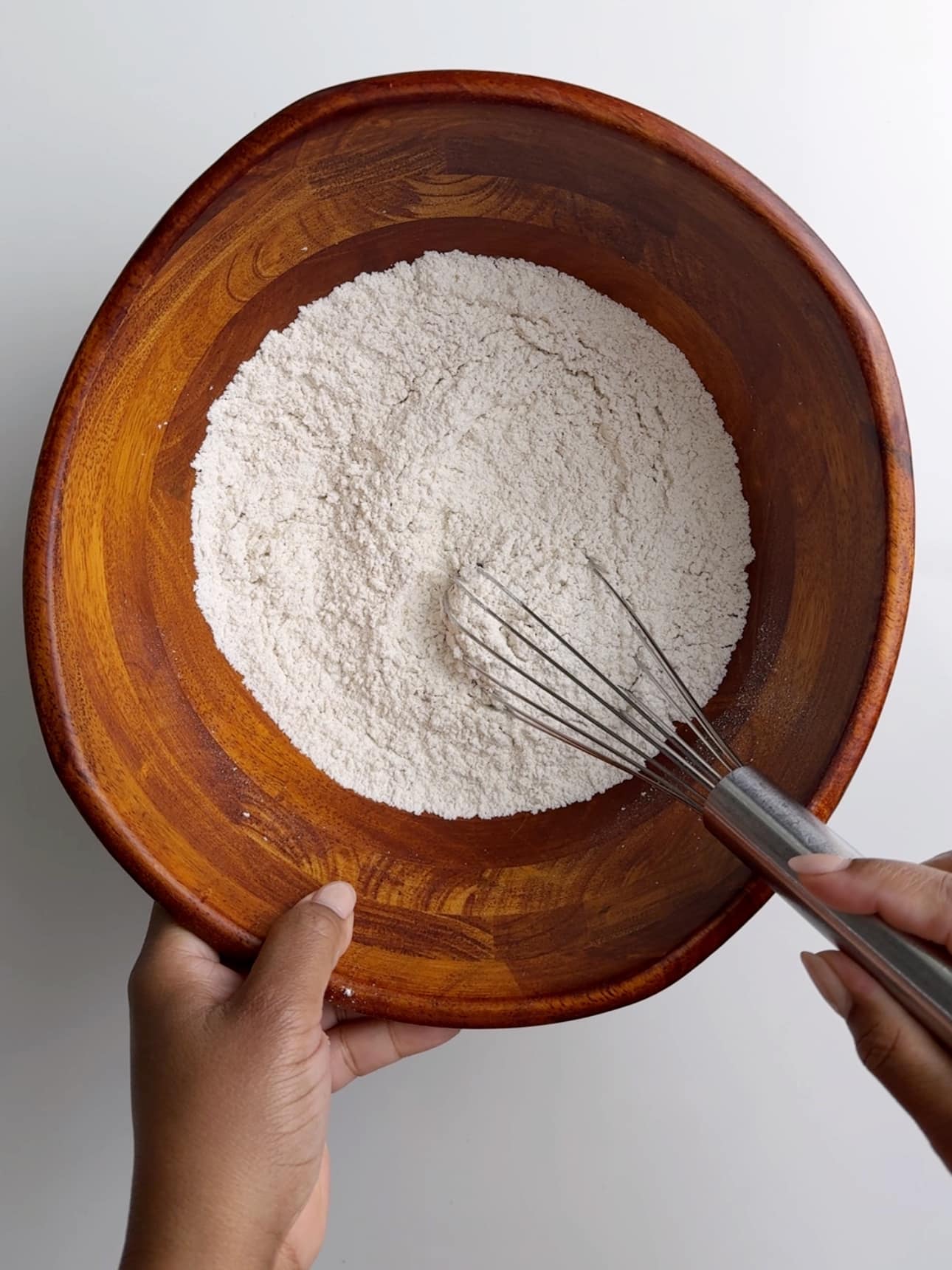 Mixing together all of the dry ingredients for gluten free hot cross buns with a wire whisk.