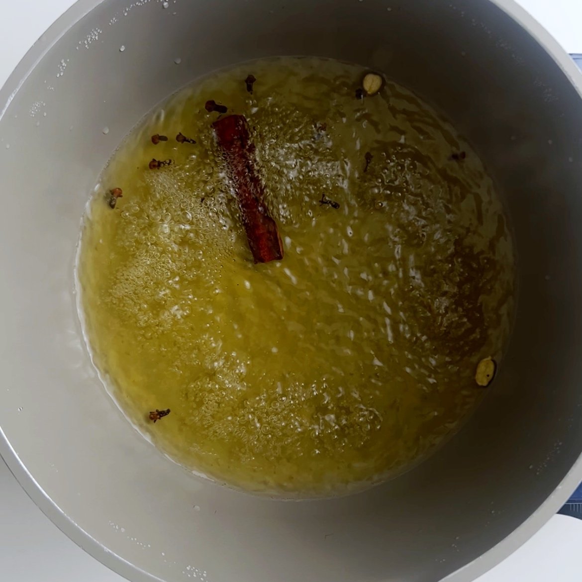 Spices boiling in water in a gray pot