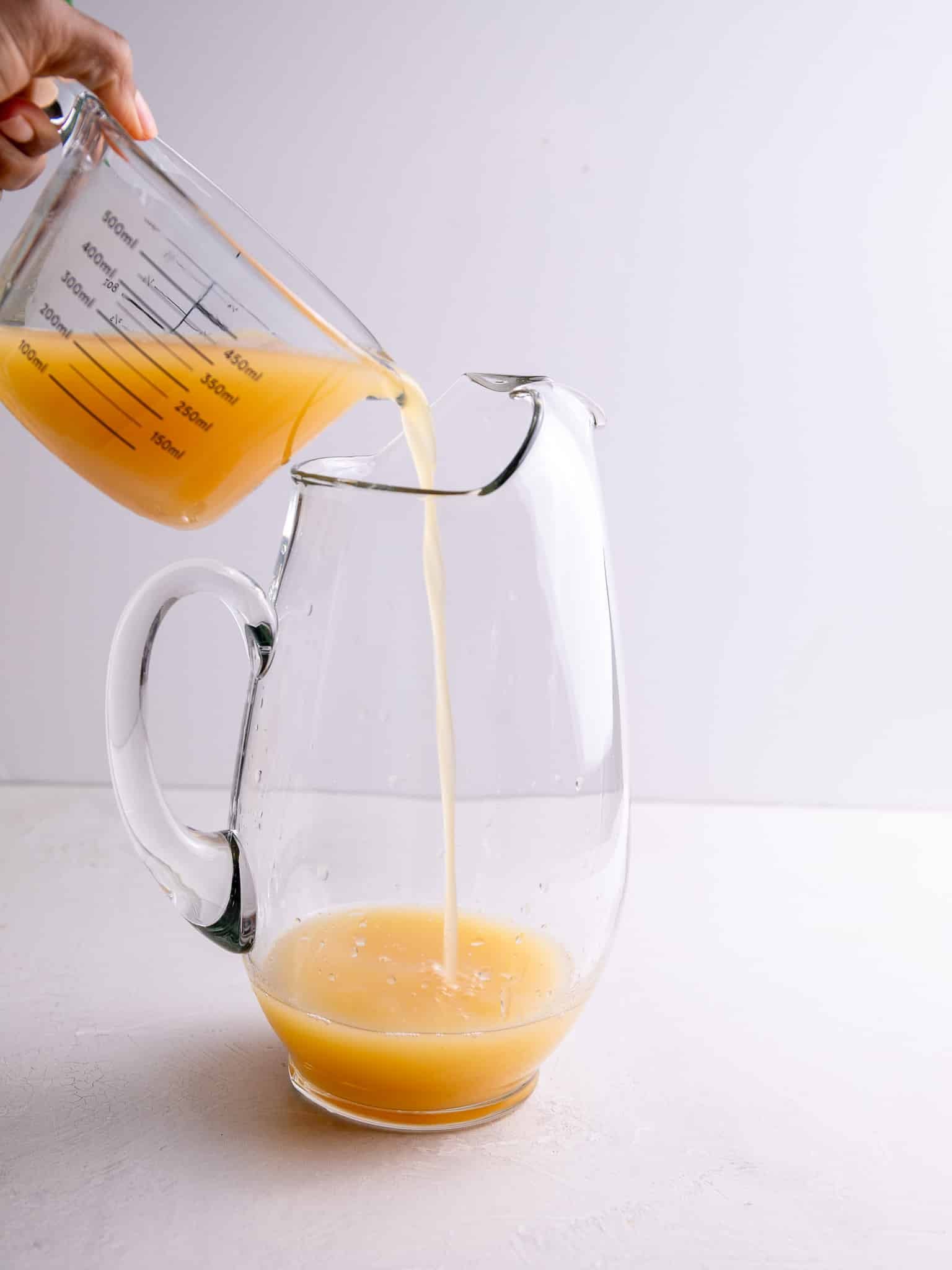 Pouring tropical fruit juices into a pitcher for Caribbean rum punch