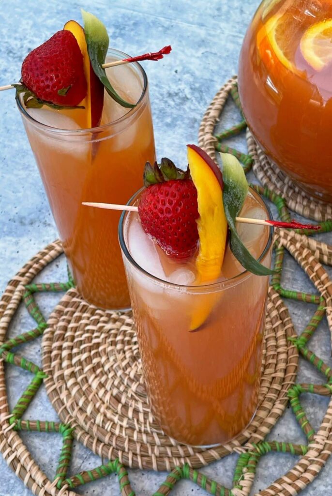 two garnished glasses of Caribbean rum punch alongside a pitcher