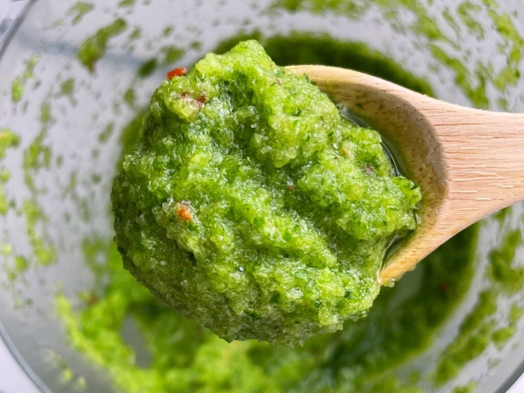 a spoonful of green seasoning over a bowl of the marinade