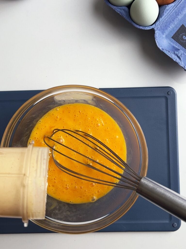 Beaten eggs in a bowl with a whisk for Whole30 egg bites