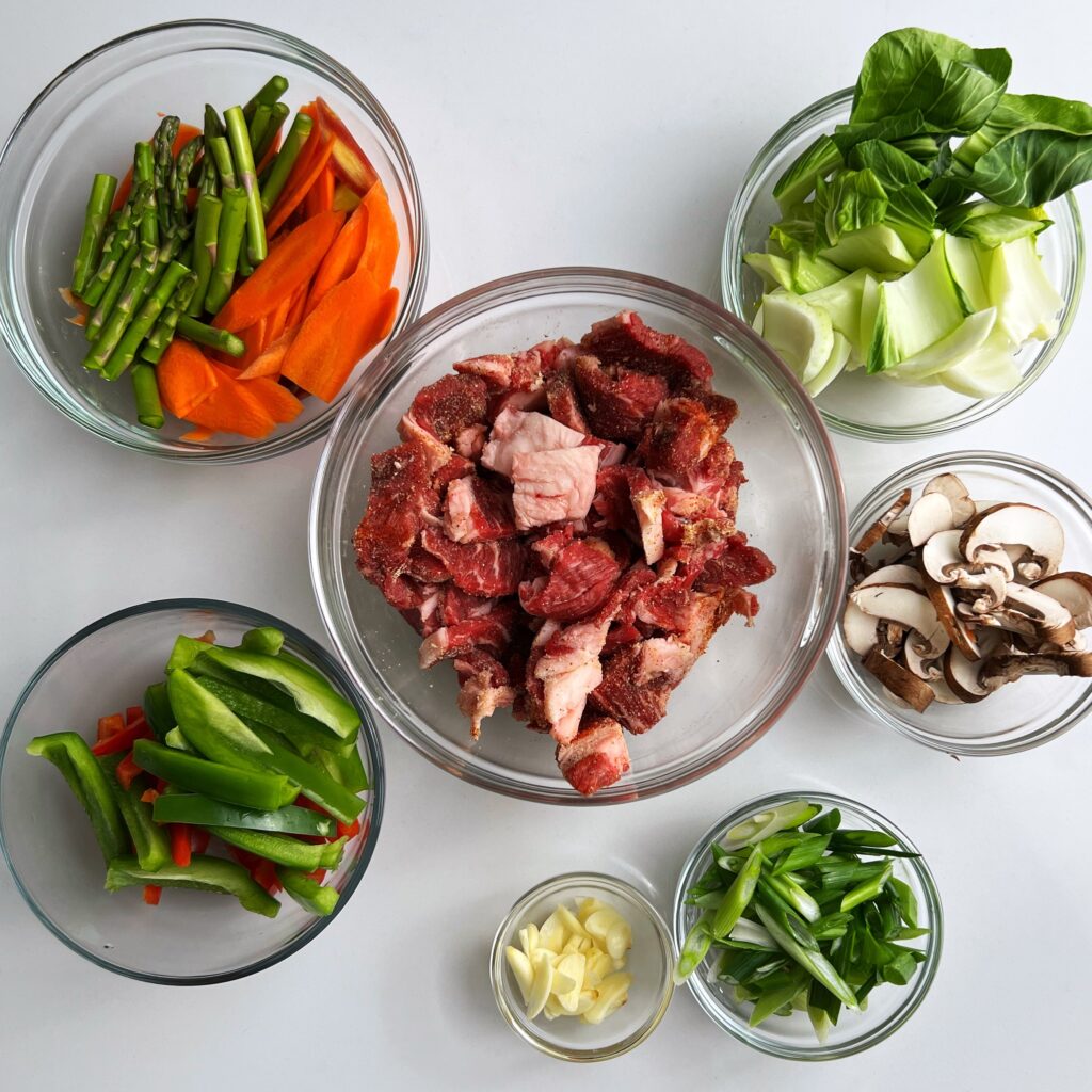 Stir fry ingredients in glass bowls on a white counter