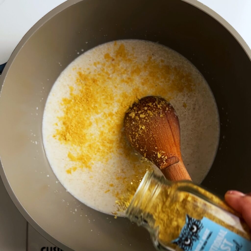Adding nutritional yeast to farine grits in a pot
