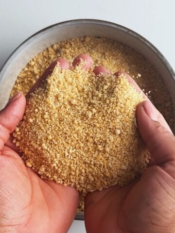 Farine in brown hands over a bowl.